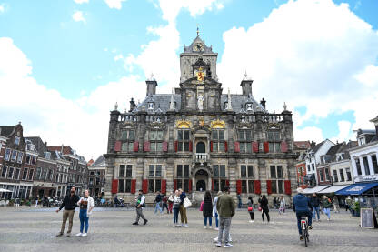 Delft, Nizozemska. Ljudi šetaju na glavnom gradskom trgu. Zgrade u centru grada.