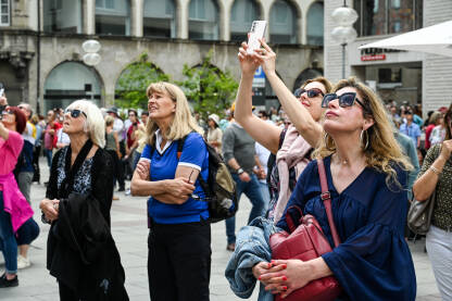 Turisti fotografiraju znamenitosti u centru grada. Ljudi snimaju mobilnim telefonima.