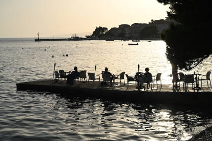Turisti uživaju na molu u ljetno predvečerje. Jadransko more, Hrvatska.