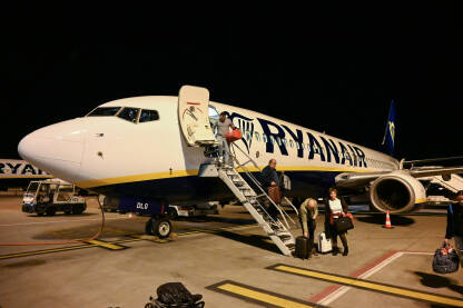 Putnici se iskrcavaju iz Ryanair Boeinga 737-800 noću. Iskrcavanje putnika s komercijalnog leta na aerodromu. Let avionom.