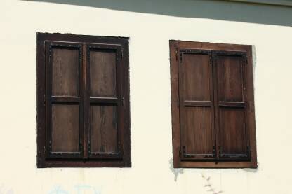 Stari drveni dekorativni prozori sa zatvorenim krilima, bela fasada na kuci