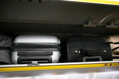 Putnički koferi u kabini aviona. Prtljag putnika u avionu. Putne torbe. Ručni prtljag.