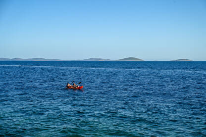 Ljudi veslaju na kajaku u moru. Vožnja kajakom. Rekreacija na vodi. Turisti na odmoru.