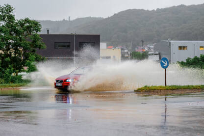 Automobil ide kroz vodu.Nakon lokalni pljuskova Tuzlanske ulice pod vodom,otezano odvijanje saobraćaja.