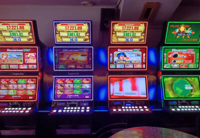 Kockarski automati koje izazivaju zavisnost. Niz elektronskih video slot mašina u kazinu. Jarko osvijetljen enterijer kazina.