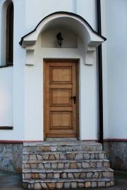 Vrata od drvena na beloj zgradi sa fenjerom iznad vrata
