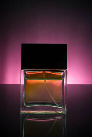 Staklena bočica parfema na tamnoj reflektirajućoj pozadini