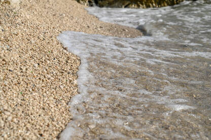 Morski valovi na plaži sa sitnim zlatnim pijeskom. Talasi na obali mora ljeti.