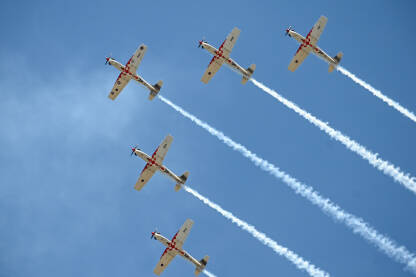 Avioni na plavom nebu tokom aeromitinga. Pet aviona u formaciji.  Airshow.