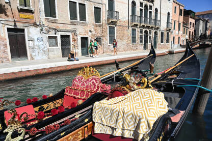 Venecija, Italija. Gondole u kanalu u gradu. Turisti istražuju grad.