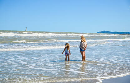 Majka sa kćerkom na pješčanoj plaži. Majka sa djetetom na moru. Turisti na godišnjem odmoru.