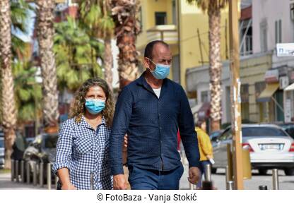 Par srednjih godina hoda ulicom sa maskama na licu, zbog pandemije virusa korona. Muškarac i žena šetaju ulicama Drača, Albanija.