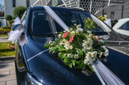 Ukrašen automobil cvijećem i trakama. Dekoracija vozila za mladence. Automobil za vjenčanje. Ukrašeni automobil u svatovima.