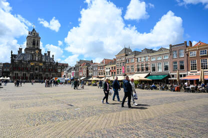 Delft, Nizozemska. Ljudi šetaju na glavnom gradskom trgu. Zgrade u centru grada.