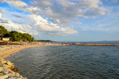 Makarska, Hrvatska. Ljudi uživaju na plaži uz more. Turisti na pješčanoj plaži tokom zalaska sunca. Godišnji odmor.