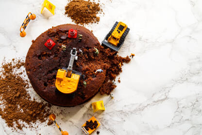 Figurice građevinskih mašina i radnika koji kopaju čokoladnu tortu.