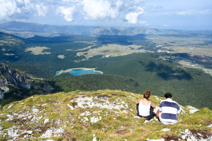 Planinari na vrhu planine. Šuma i jezero.
