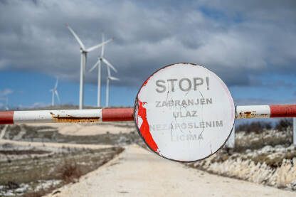 Tabla sa natpisom: Stop zabranjen pristup nezaposlenim licima. Vjetrenjače na brdu. Proizvodnja električne energije iz vjetra.