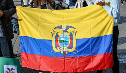 Zastava Ekvadora. Ljudi drže nacionalnu zastavu Ekvadora. Grb