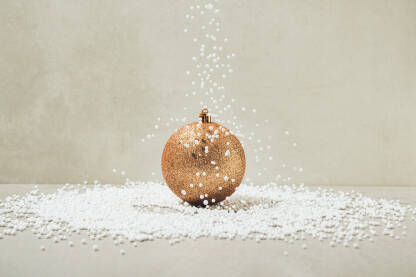 Zlatna sjajna božićna / novogodišnja kuglica na koju pada umjetni snijeg.