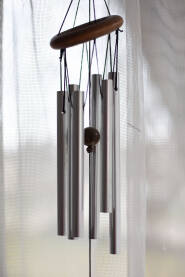 Zvono na ulaznim vratima od cevcica i kugle drveta, zavesa na prozoru