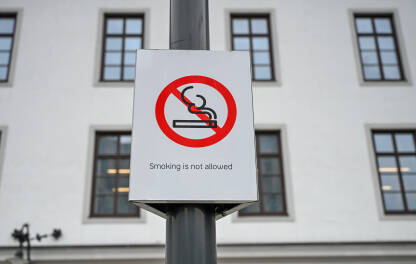 Javni znak zabrane pušenja s prekriženom cigaretom na ulici. Znak "zabranjeno pušenje" na gradskom trgu. Znak zabrane pušenja na otvorenom.