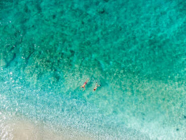Turisti se kupaju u moru. Snimak dronom kupača u vodi. Djevojka i momak se kupaju u toplom tropskom moru ljeti.