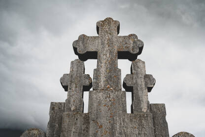 Stari kameni križ / krst sa tmurnim i dramatičnim oblacima u pozadini. Staro groblje.