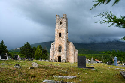 Ruševine stare crkve sa dramatičnim kišnim oblacima u pozadini.