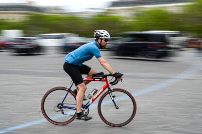 Zamućena fotografija čovjeka koji se brzo kreće na biciklu na ulici. Vožnja biciklom po gradu.