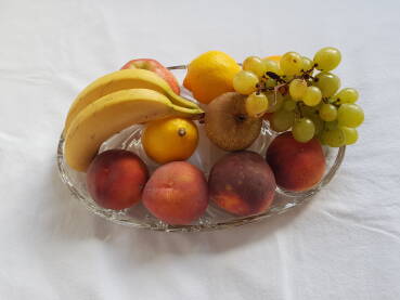 Voćni miks u staklenoj zdjeli (banane, breskve, jabuke, grožđe, limun i narandža)