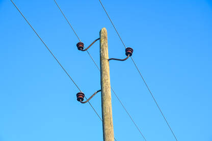 Bandera sa okačenim kablovima za električnu struju. Stub za struju u prirodi sa kablovima koji provode električnu energiju. Visokonaponski električni vod. Napon.