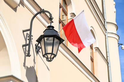 Zastava Poljske na jarbolu na zgradi. Poljska zastava vijori na vjetru. Bijela i crvena boja na poljskoj zastavi.