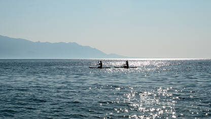 Muškarac i djevojka surfaju na dasci. Sport i rekreacija na moru tokom ljeta. Stand up paddle (SUP).