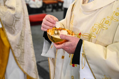 Svećenik vjernicima daje sakramentalni kruh. Katolički svećenik daje pričest u katedrali.