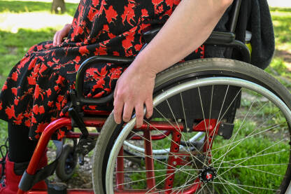 Žena u invalidskim kolicima. Djevojka sjedi u invalidskim kolicima u parku. Invaliditet. Rehabilitacija.