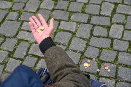 Siromah prosi novac. Ruka starca drži kovanice. Gladan beskućnik traži novac. Siromaštvo.