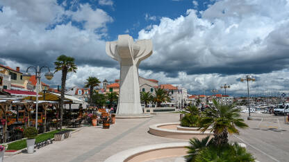 Vodice, Hrvatska. Turisti šetaju centrom grada. Spomenik NOB u centru grada. Mala luka na Jadranskom moru.
​