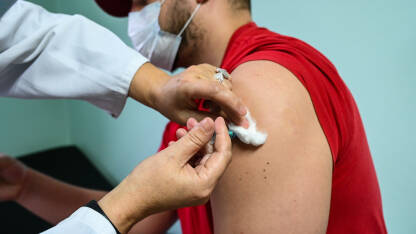 Čovjek prima vakcinu u rame. Covid vakcinacija. Doktor ubrizgava pacijentu antivirusnu vakcinu Covid-19. Vakcinacija protiv korona virusa.