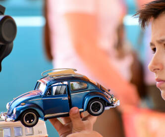 Dječak pokazuje igračku starog automobila plave boje