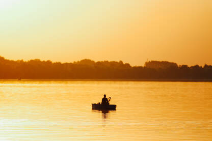 Ribar u čamcu tokom zalaska sunca na rijeci Savi u Brčkom