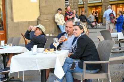 Turisti piju piće na terasi restorana. Ljudi sjede u kafiću.