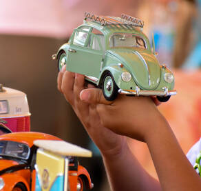 Dječak drži retro automobil igračku. Minijatura starog automobila. Vrata na autu su otvorena.