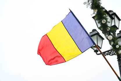 Rumunjska zastava na jarbolu. Plava, žuta i crvena boja rumunjske zastave.