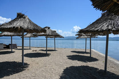 Suncobrani na pješčanoj plaži blizu vode. Egzotična plaža ljeti. Koncept odmora, putovanja i turizma.