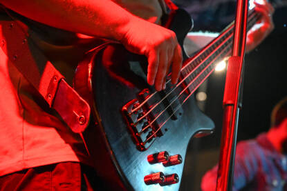 Muzičar svira bass gitaru na koncertu. Krupni plan muškarca koji svira bass gitaru na festivalu.