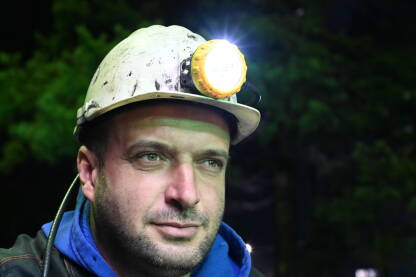 Portret rudara u rudniku. Rudar s kacigom i svjetiljkom na poslu.