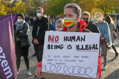 Djevojka na protestu. Promigrantske demonstracije. Djevojka sa maskom na licu protestvuje na ulici.