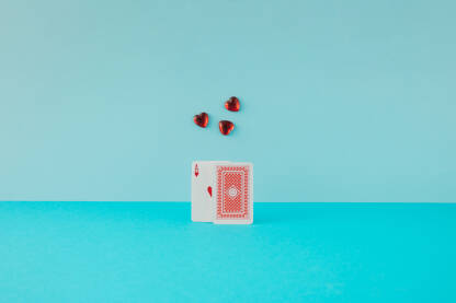 Karte za igranje s crvenim asom srce i tri staklena srca na plavoj pozadini.