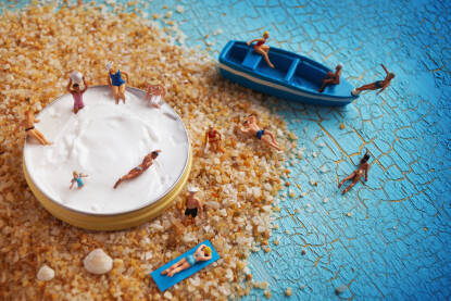 Ilustracija male pješčane plaže sa figuricama ljudi u kremi za sunčanje.